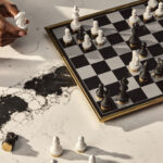 A chessboard and drinks atop white Calacatta Scoria quartz with bold oversized black veins.