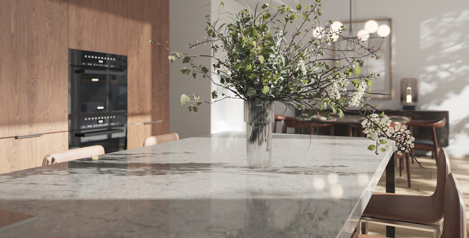 A kitchen island of mild-gray Symphony Grey quartz with delicate white tones and diagonal silvery streaks.