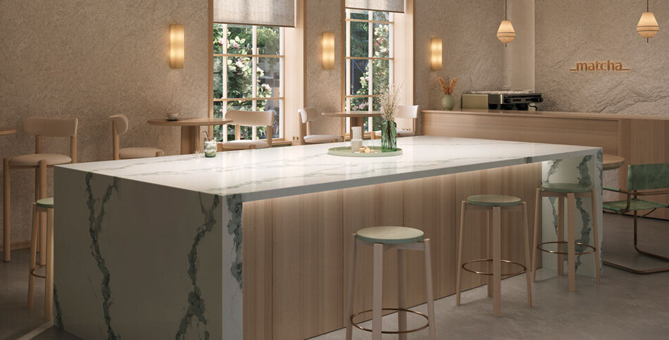 Island bar with a white Calacatta Thyme Caesarstone ICON waterfall edge counter, large woven rattan pendant lighting, and light wood paneling.