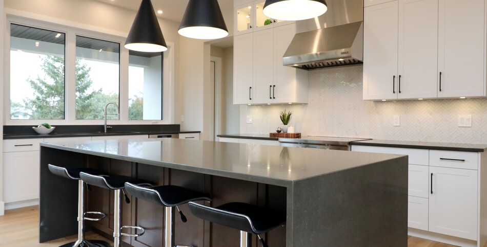 Kitchen island with a waterfall edge of smooth slate-inspired Piatra Grey quartz with chalky white veins in a marble design.