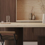 Light-beige kitchen island and backsplash of Travina porcelain with rich, dark brown wood cabinetry and a sculptural pendant light.