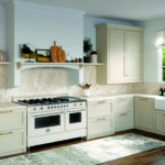 Kitchen with cream Shaker-style cabinets, light-beige Fume porcelain countertops and backsplash, a cream professional range, and dark wood flooring.