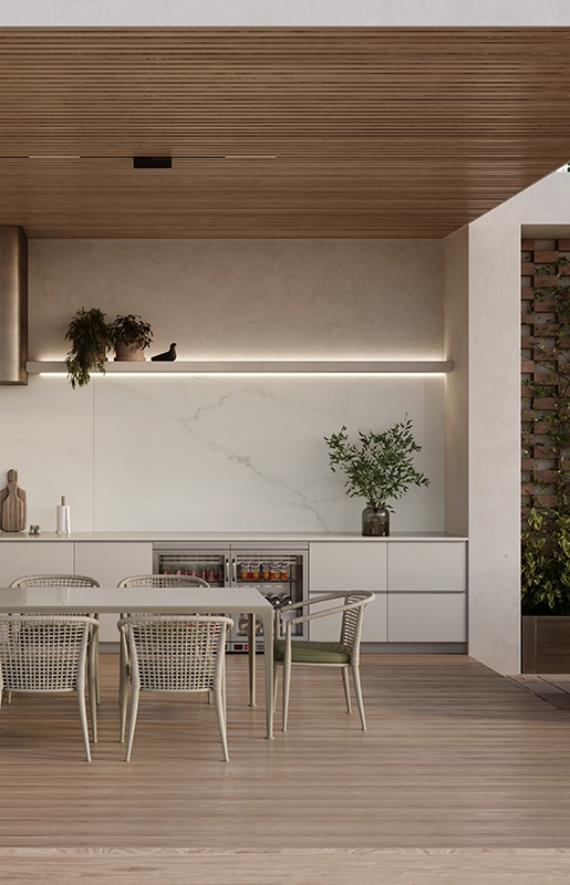 Modern outdoor kitchen with dining table, white chairs, grill, plants, and wooden ceiling.