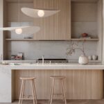 Monochromatic kitchen in warm neutrals with herringbone floor and thick stone island of Caesarstone ICON™ advanced fusion material in Calacatta Lacebound.