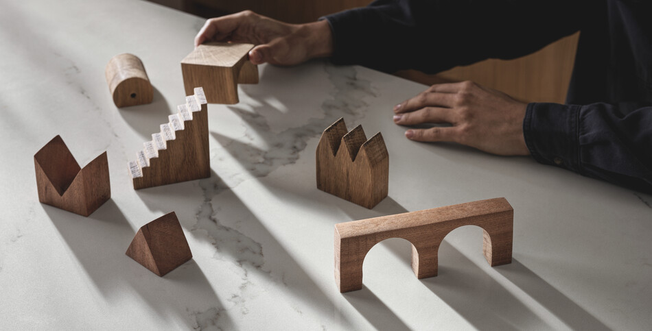 Wooden blocks sit atop an advanced fusion countertop of Calacatta Nobella, a silica-free* quartz alternative, with light-gray veins, accented by warm copper tints.