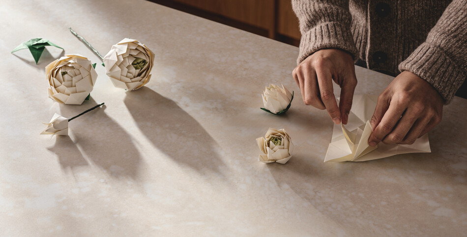 Origami roses sit on a countertop of Caesarstone ICON in Moonflow, a bone-white base enriched with layers of creams and beiges.
